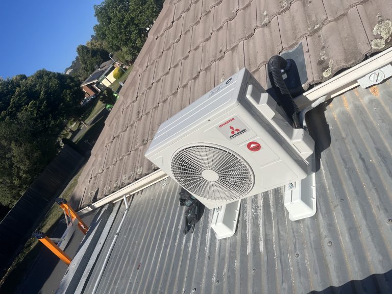 Outdoor Mitsubishi inverter air conditioning unit mounted on roof surface.