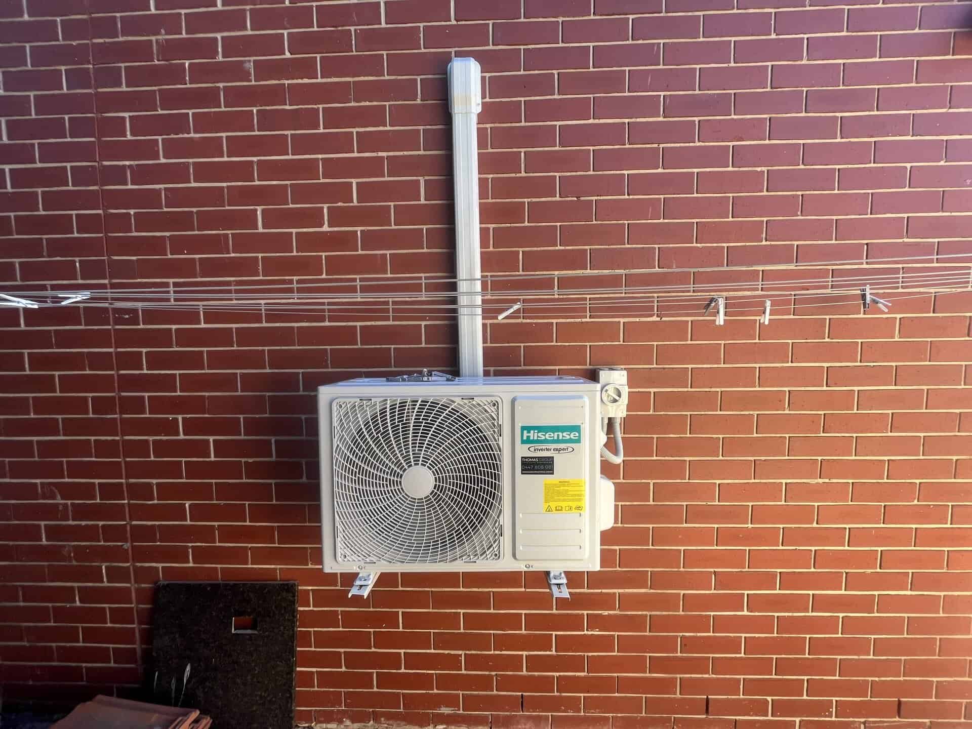 Outdoor air conditioning unit mounted on a red brick wall.