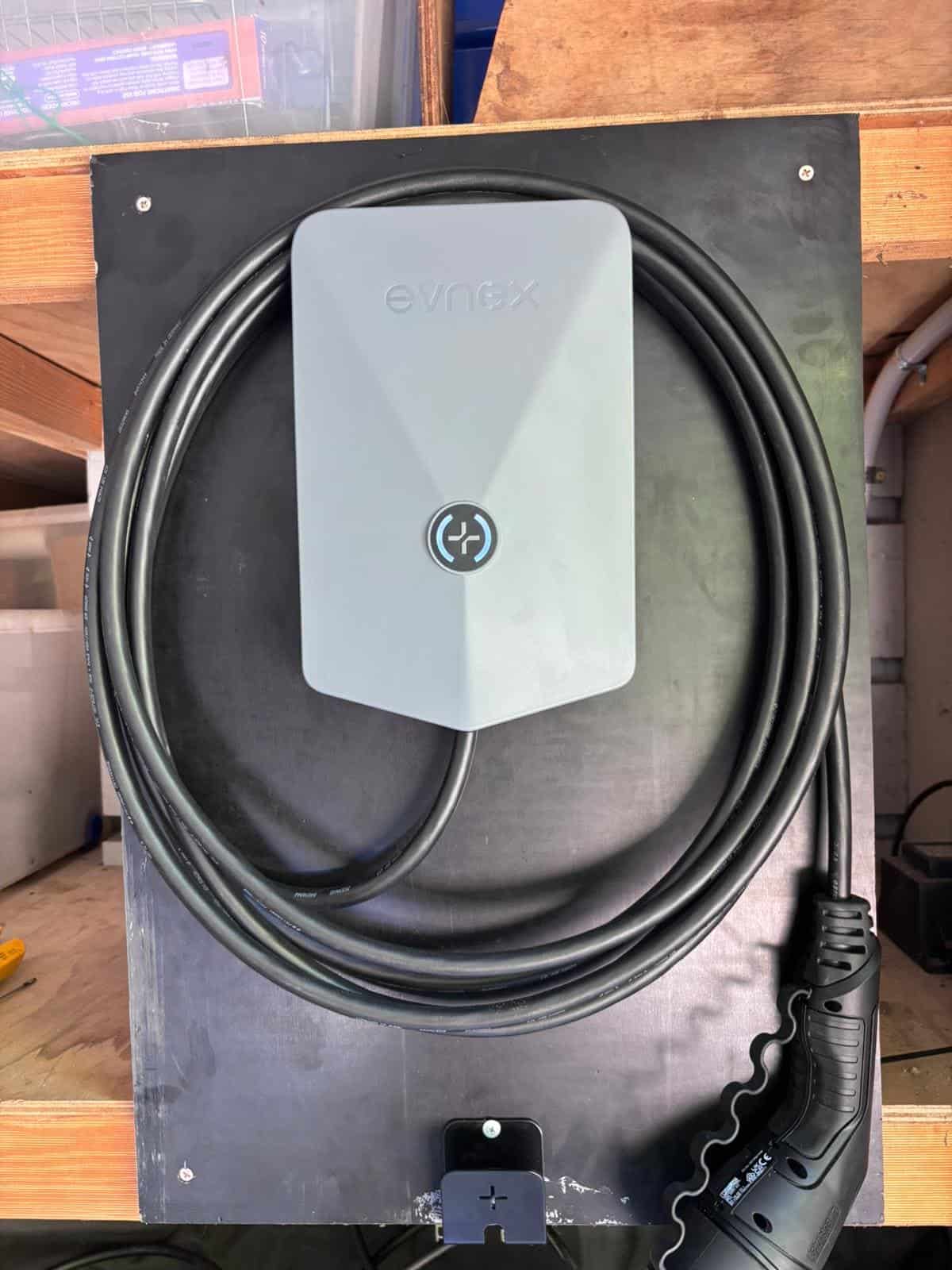Evnex electric vehicle charging station mounted on wooden surface outside.