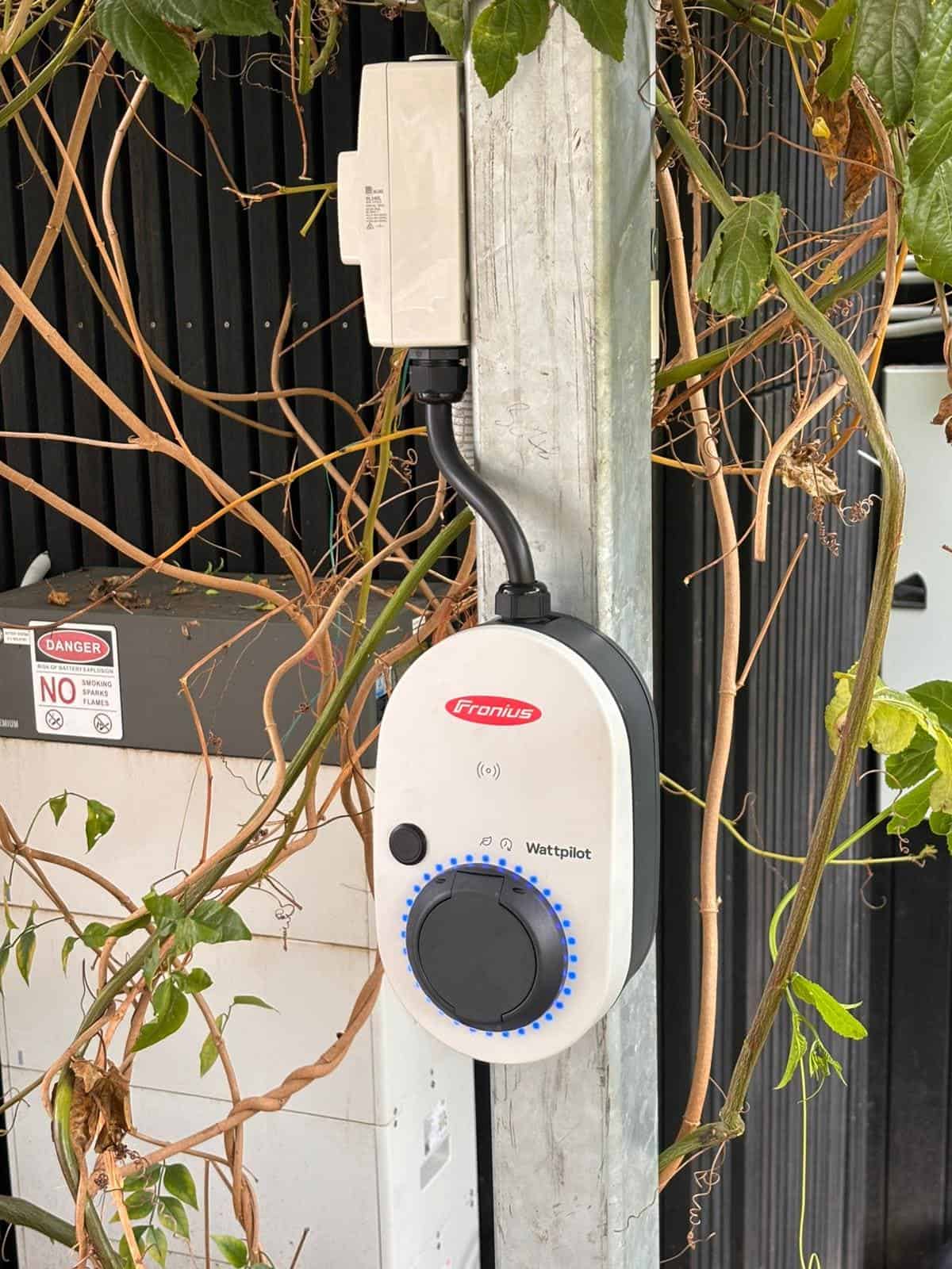 Solar power controller mounted outdoors on a metal post surrounded by climbing plants.
