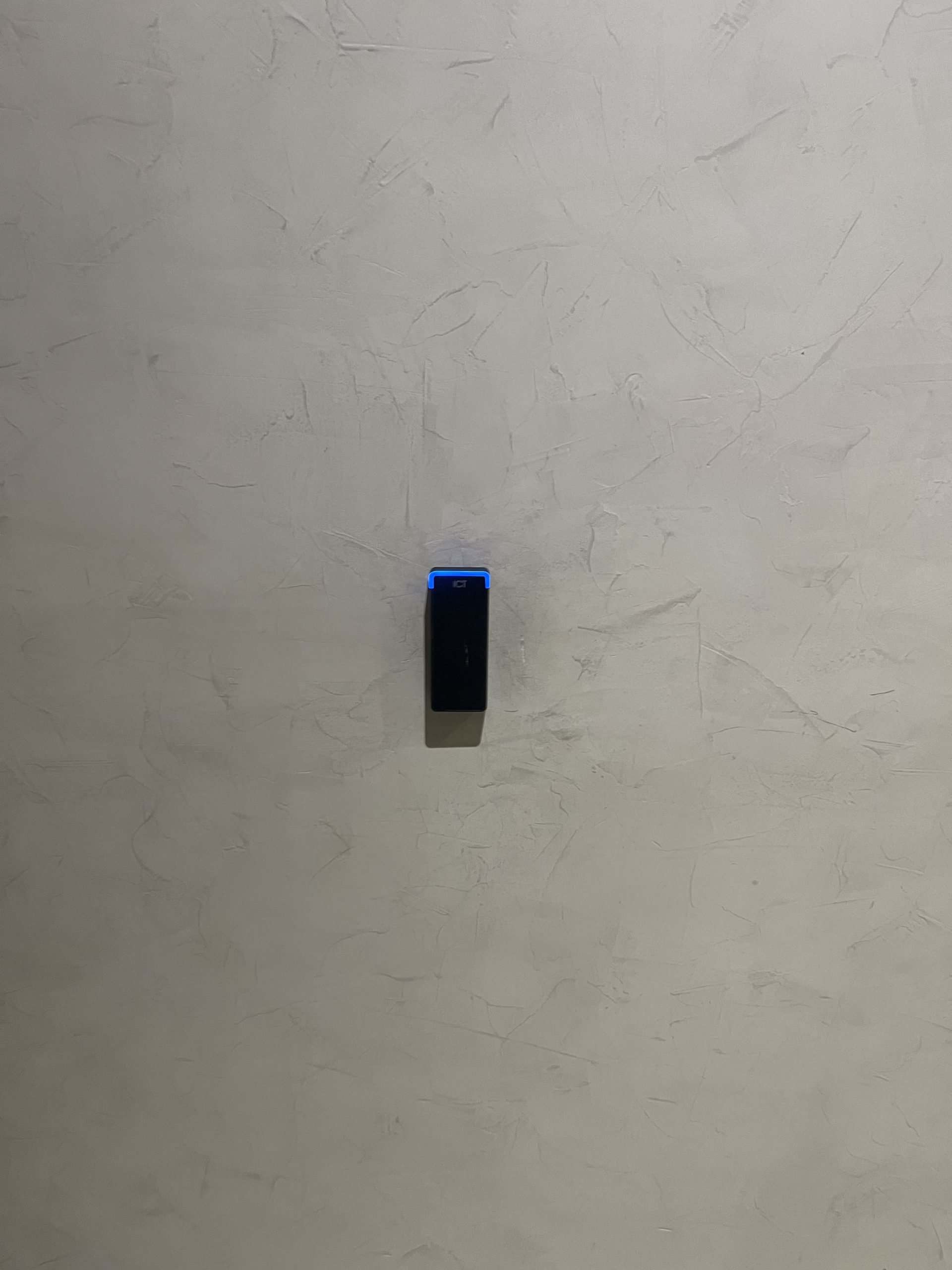 Handheld electronic device on an interior textured wall surface.