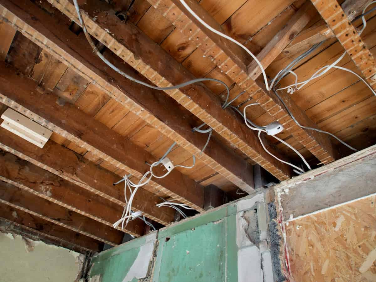 Wiring cables hanging from a wooden ceiling under construction or renovation, inside a building.