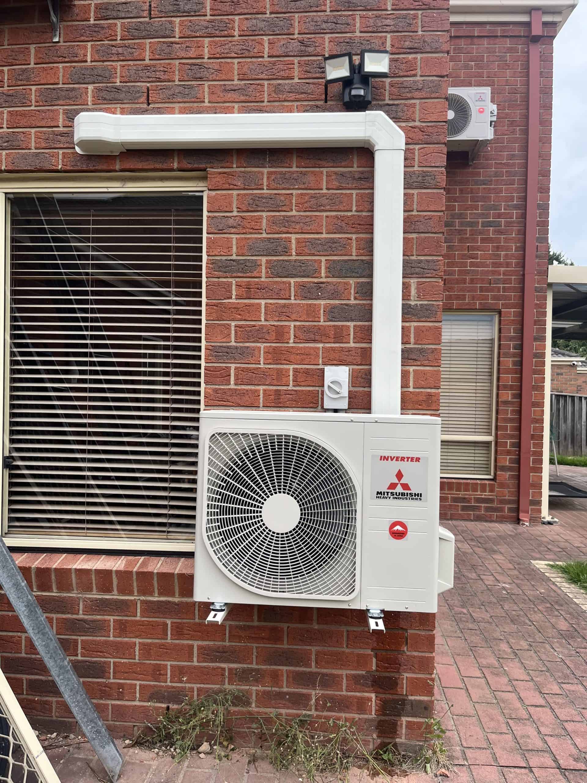 Outdoor air conditioning unit mounted on a brick wall.
