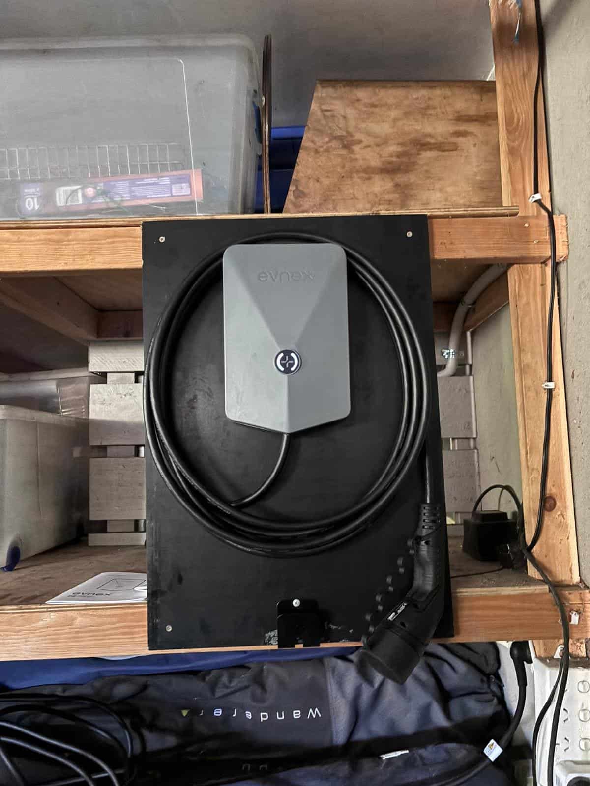 Evnax electric vehicle charger mounted on a black wooden surface indoors.