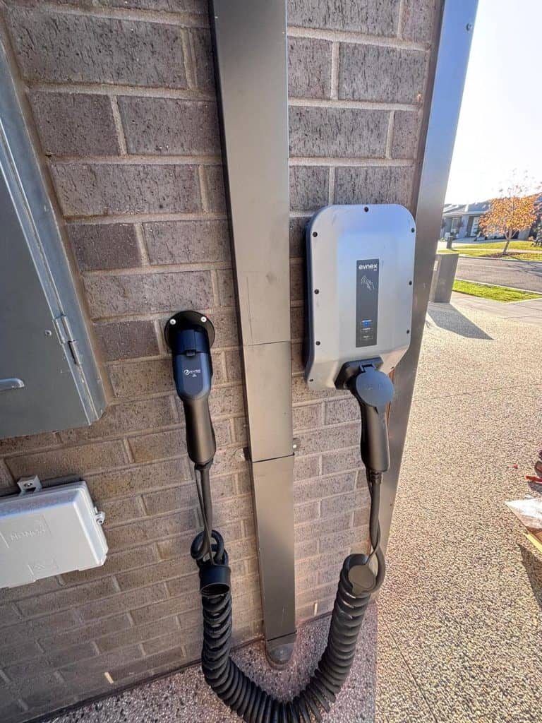 Electric vehicle charging station on a brick wall outside building.