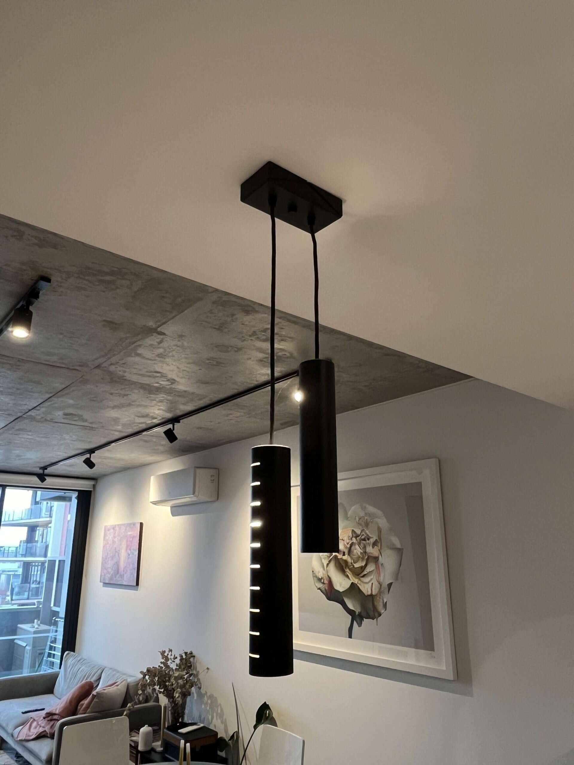 Modern black pendant lights hanging from a ceiling in a contemporary living room.