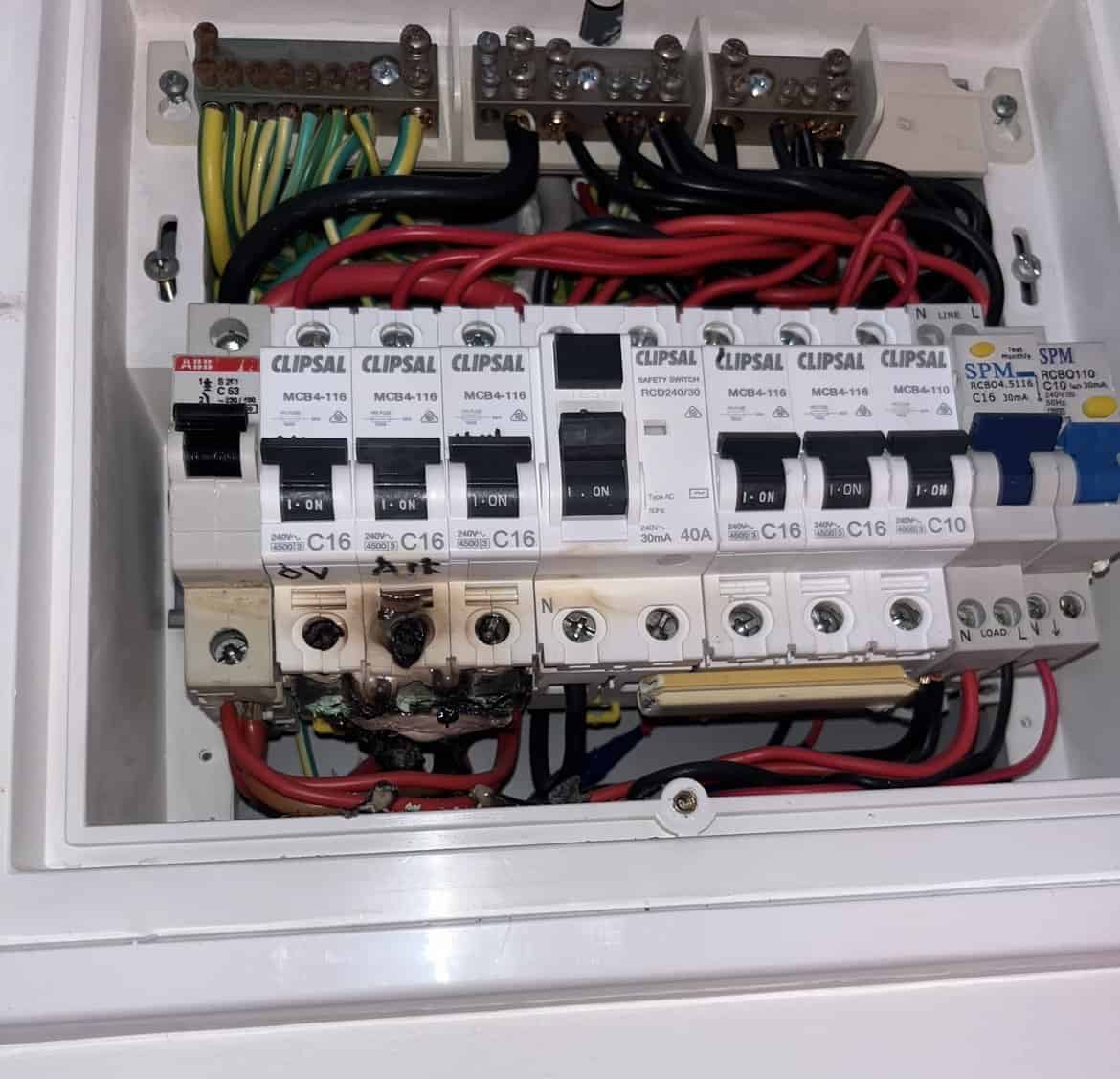 Electrical circuit breaker panel inside a white electrical box, with switches and wiring, situated indoors.